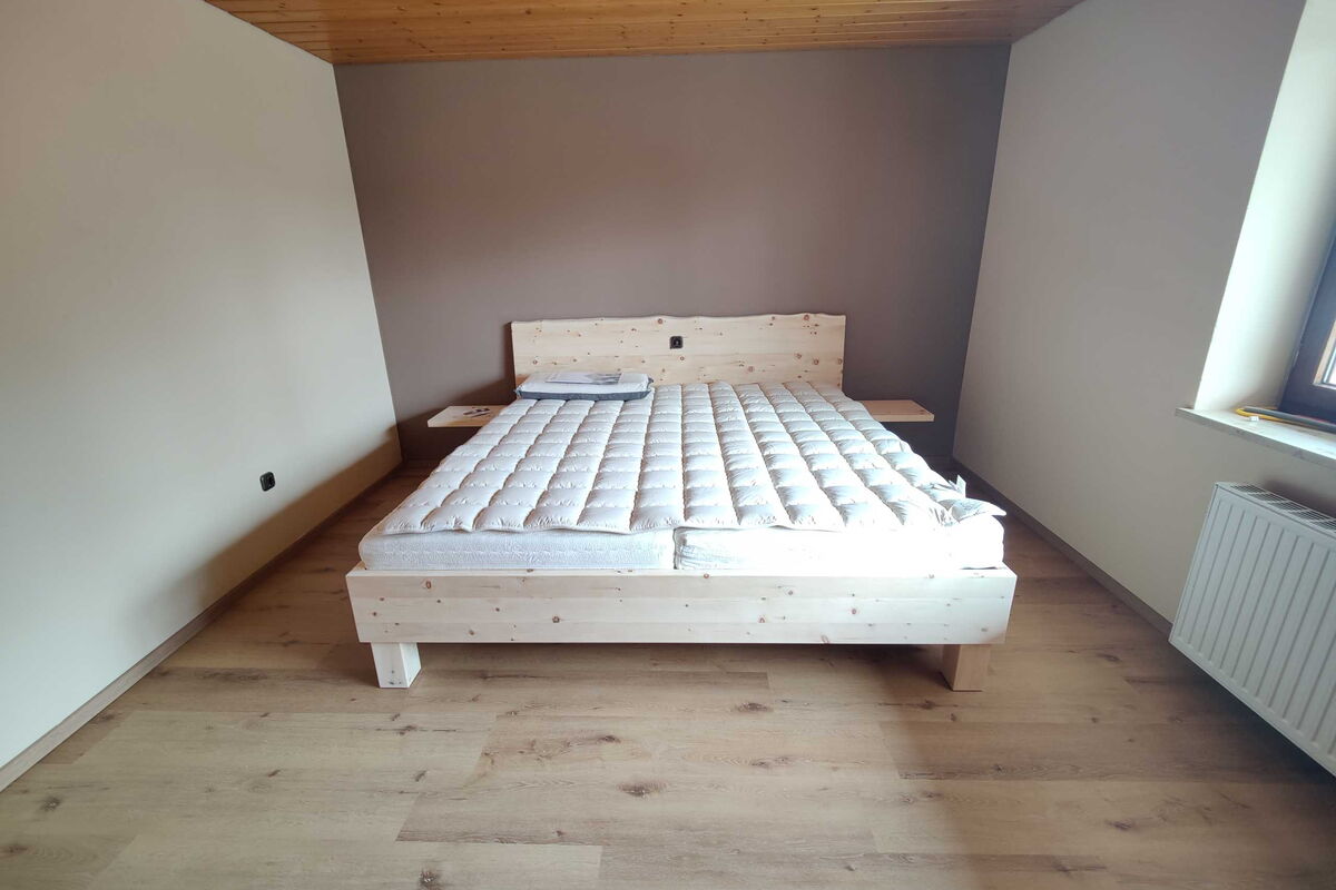 Zirbenbett Holzkirchen Sonderedition 200x200 mit Naturkante und Nachttisch